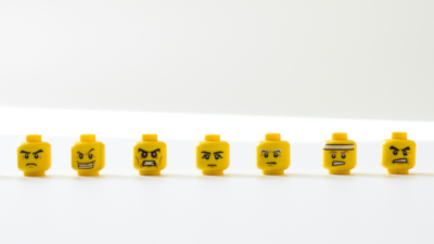 The picture shows seven yellow heads of lego figures, portraying different emotions. This symbolizes the emotions university educators go through in the process of resistance to change due to digitalisation.