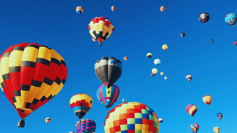 Das Bild zeigt bunte Heißluftballone vor blauem Himmel. Es ist das Titelbild unseres Forschungsprojekts "Organisationale Resilienz und Kreativität: Die Zukunft von Bildungstechnologien in der Hochschule", in dem eine Stelle für studentische Beschäftigte ausgeschrieben ist.