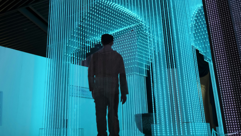 A person in a black jacket stands in a blue-lit room, symbolizing the integration of People Analytics in the workplace to enhance decision-making and employee dynamics.