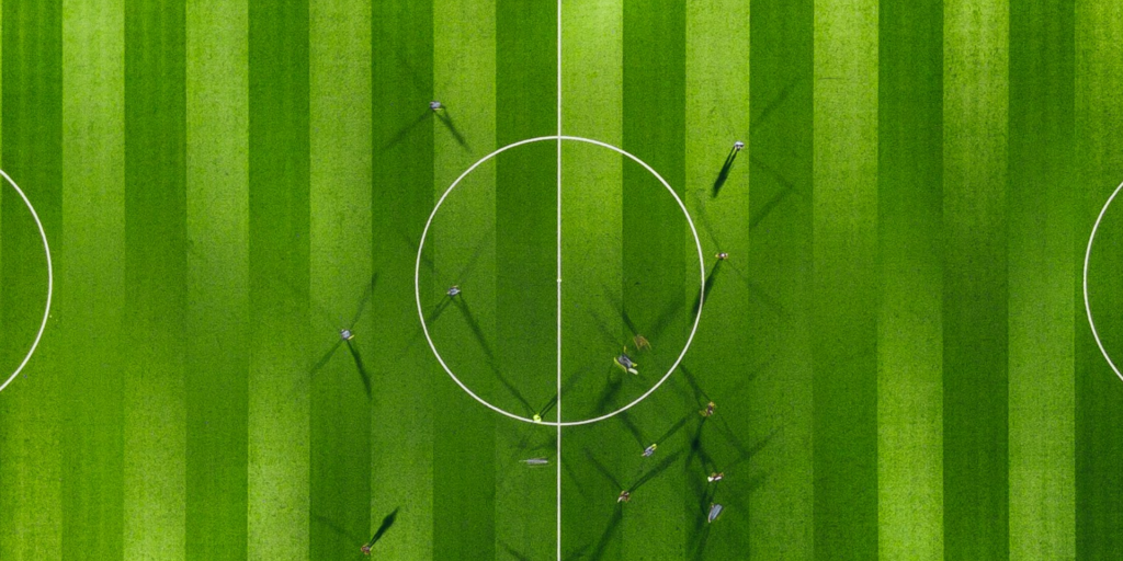 Das Bild zeigt ein Fußballfeld von oben. Die Spieler sind nur als Schatten zu erkennen, was den Human in the Loop repräsentieren soll.