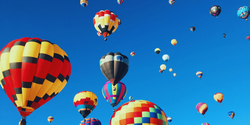 Das Bild zeigt bunte Heißluftballone vor blauem Himmel. Es ist das Titelbild unseres Forschungsprojekts "Organisationale Resilienz und Kreativität: Die Zukunft von Bildungstechnologien in der Hochschule", in dem eine Stelle für studentische Beschäftigte ausgeschrieben ist.