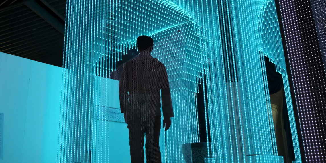 A person in a black jacket stands in a blue-lit room, symbolizing the integration of People Analytics in the workplace to enhance decision-making and employee dynamics.